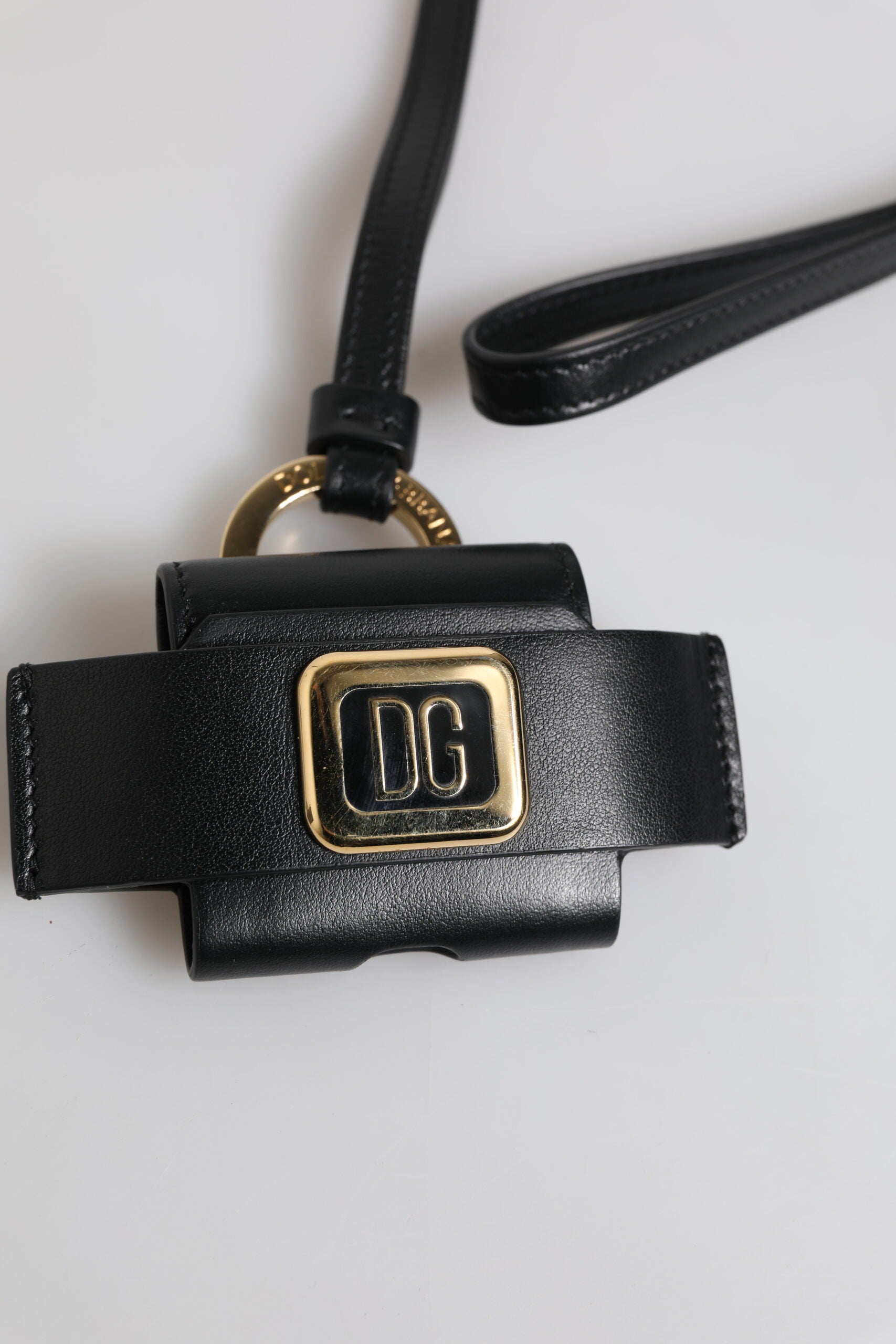 Airpods Hülle aus schwarzem Leder mit goldfarbener Metall-Logo-Plakette